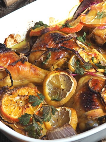 Roasted honey chicken with sliced lemons and herbs.