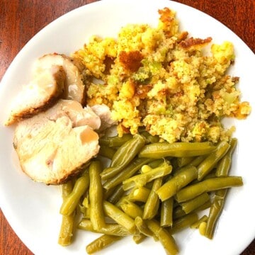 sliced pork, green beans and stuffing on white plate