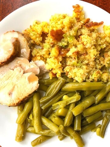 sliced pork, green beans and stuffing on white plate
