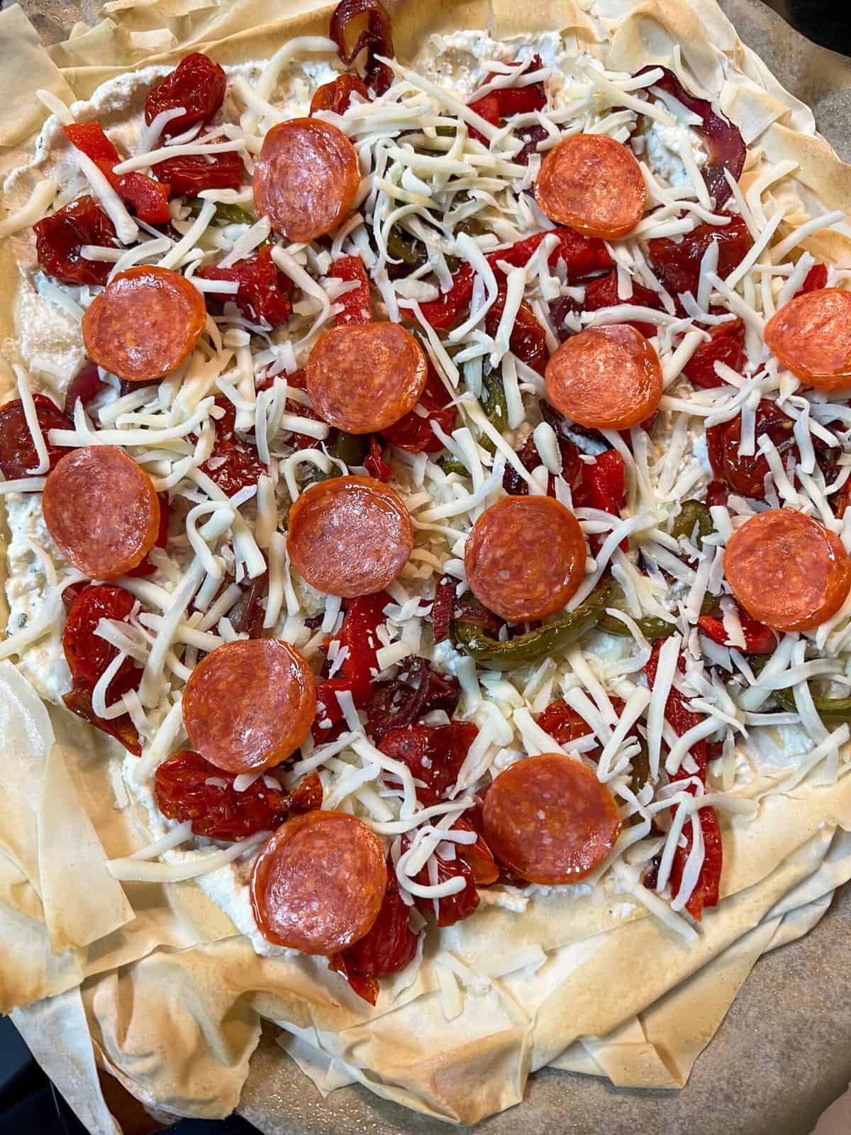 roasted veggies and pepperoni and shred cheese on phyllo crust