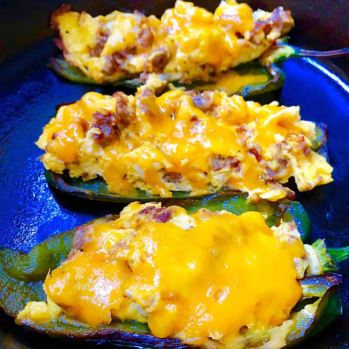 3 sausage stuffed poblanos on blue plate