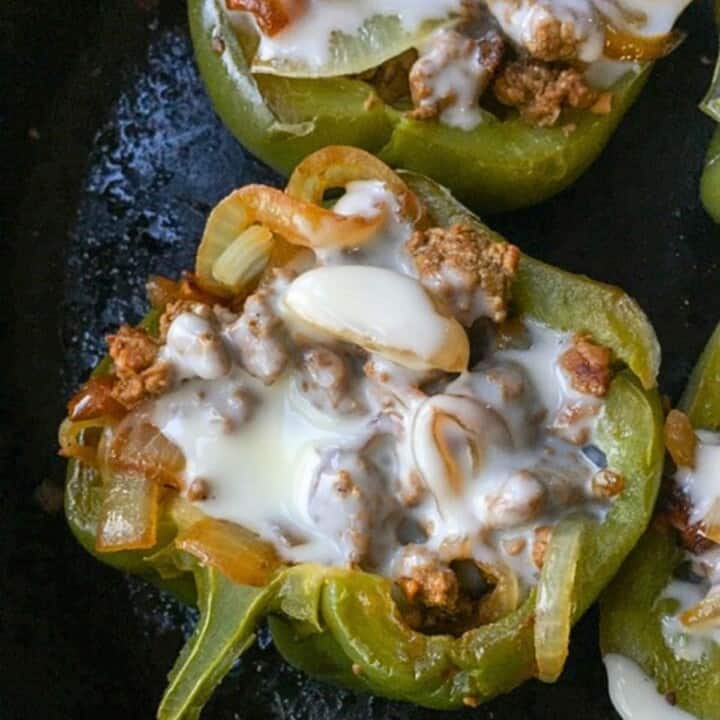 green bell peppers stuffed with cheesesteak in black skillet