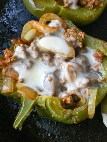 cheesesteak stuffed green pepper with melted white cheese in skillet