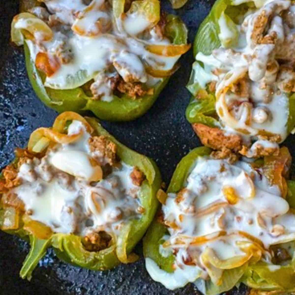 green bell peppers stuffed with cheesesteak in black skillet