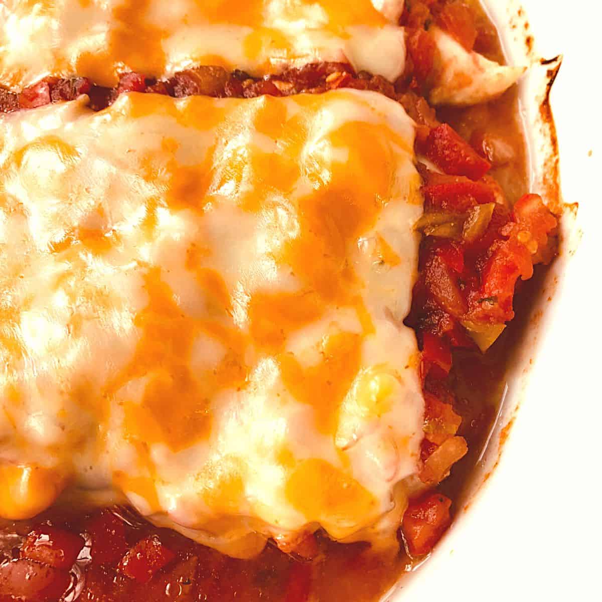 chicken tenders covered in salsa and melted cheese in white casserole