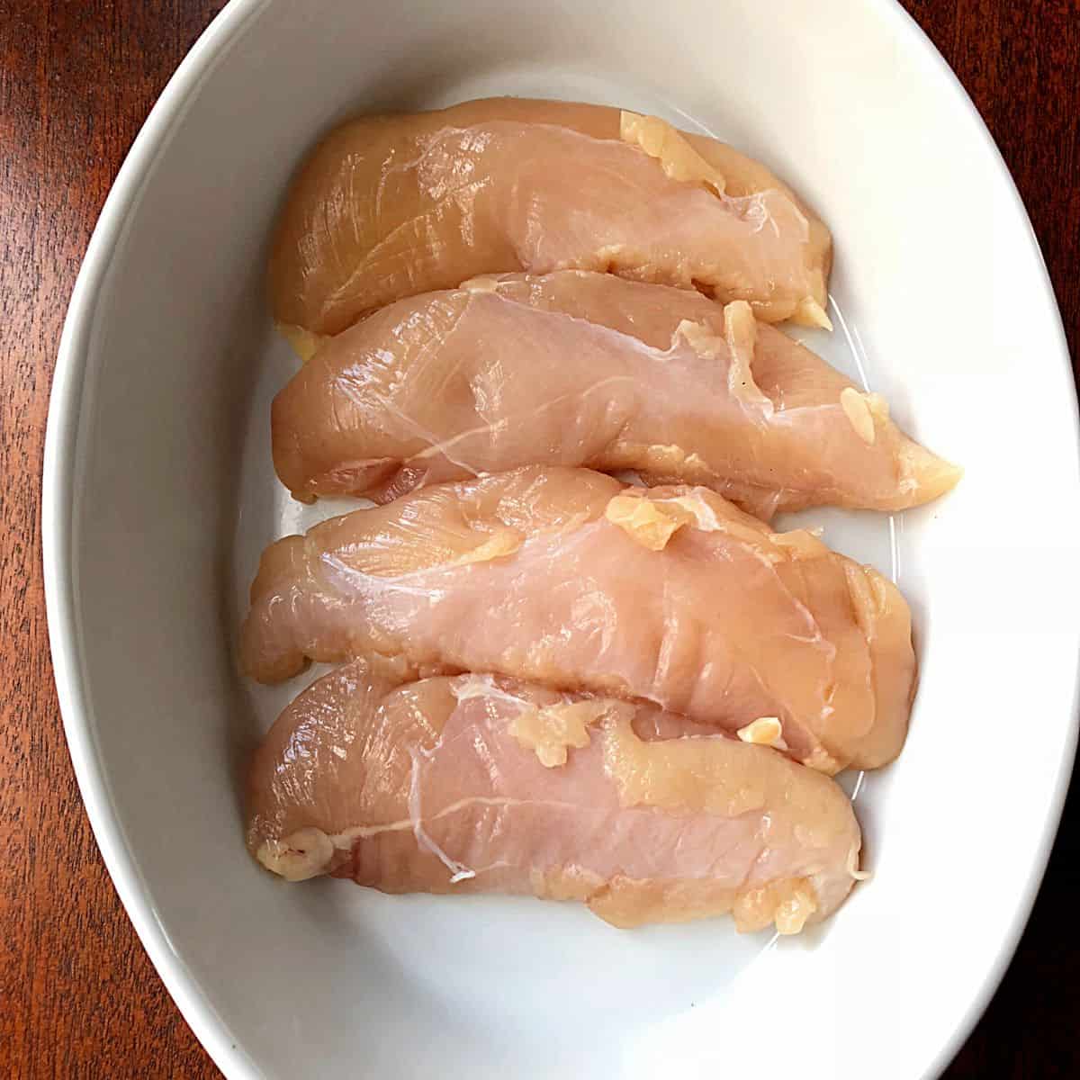raw chicken tenders in white casserole dish