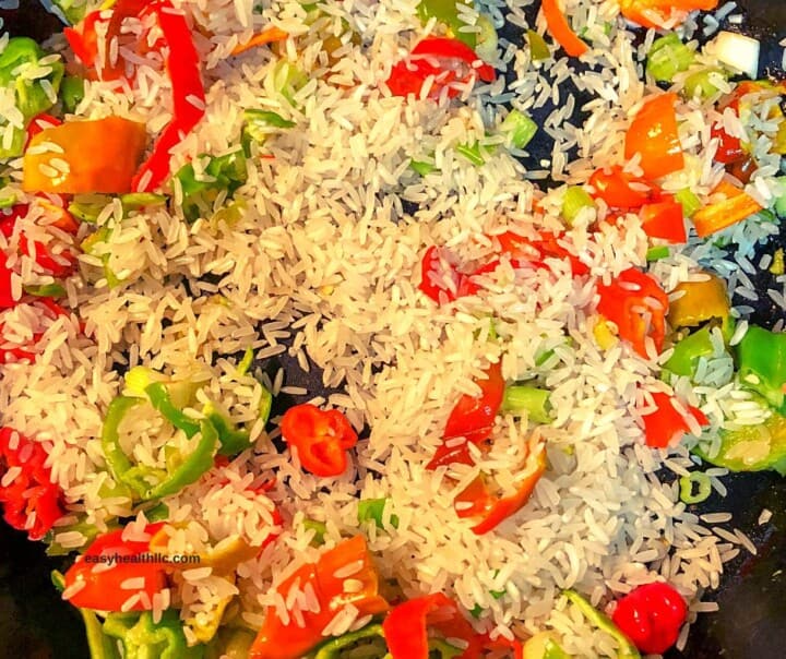 uncooked rice and veggies in skillet