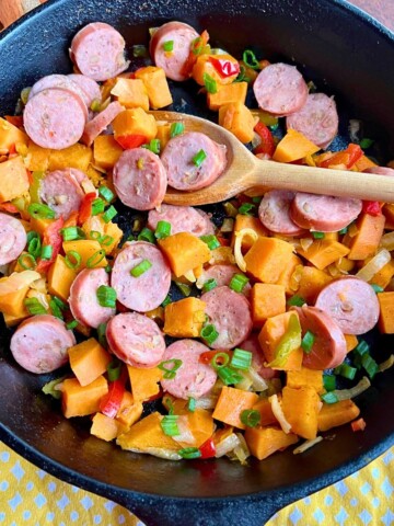 Skillet full of sweet potatoes, chicken and apple sausage and pepper and onions.