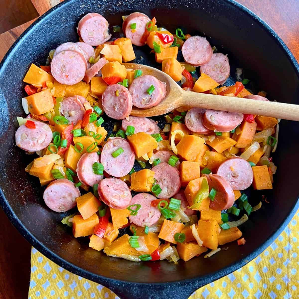 Skillet full of sweet potatoes, chicken and apple sausage and pepper and onions.