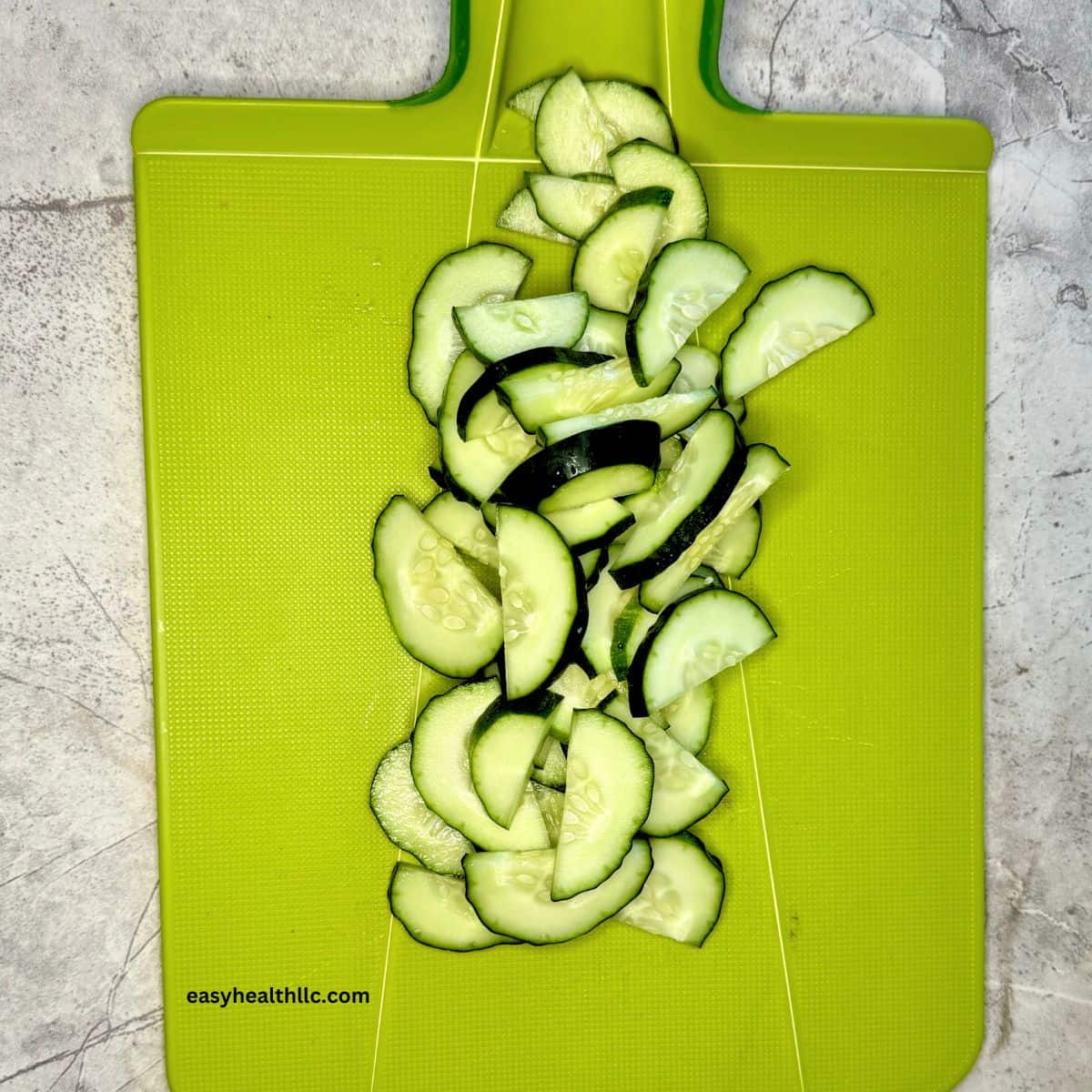 Cucumber slices on green chopping board.
