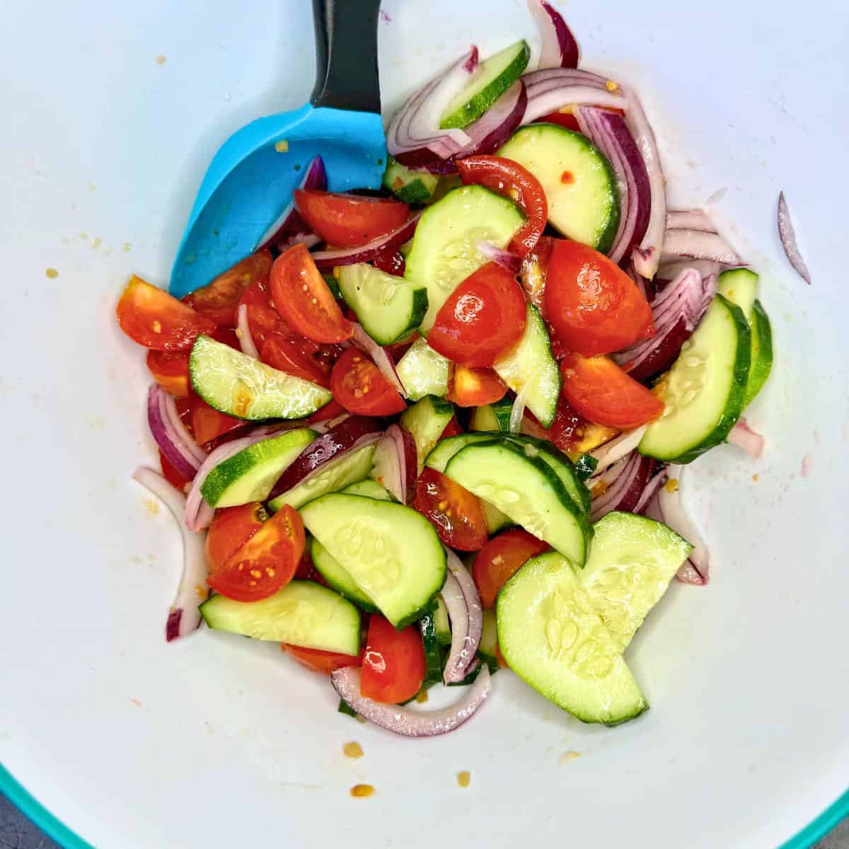Cucumber salad in bowl with spoon.