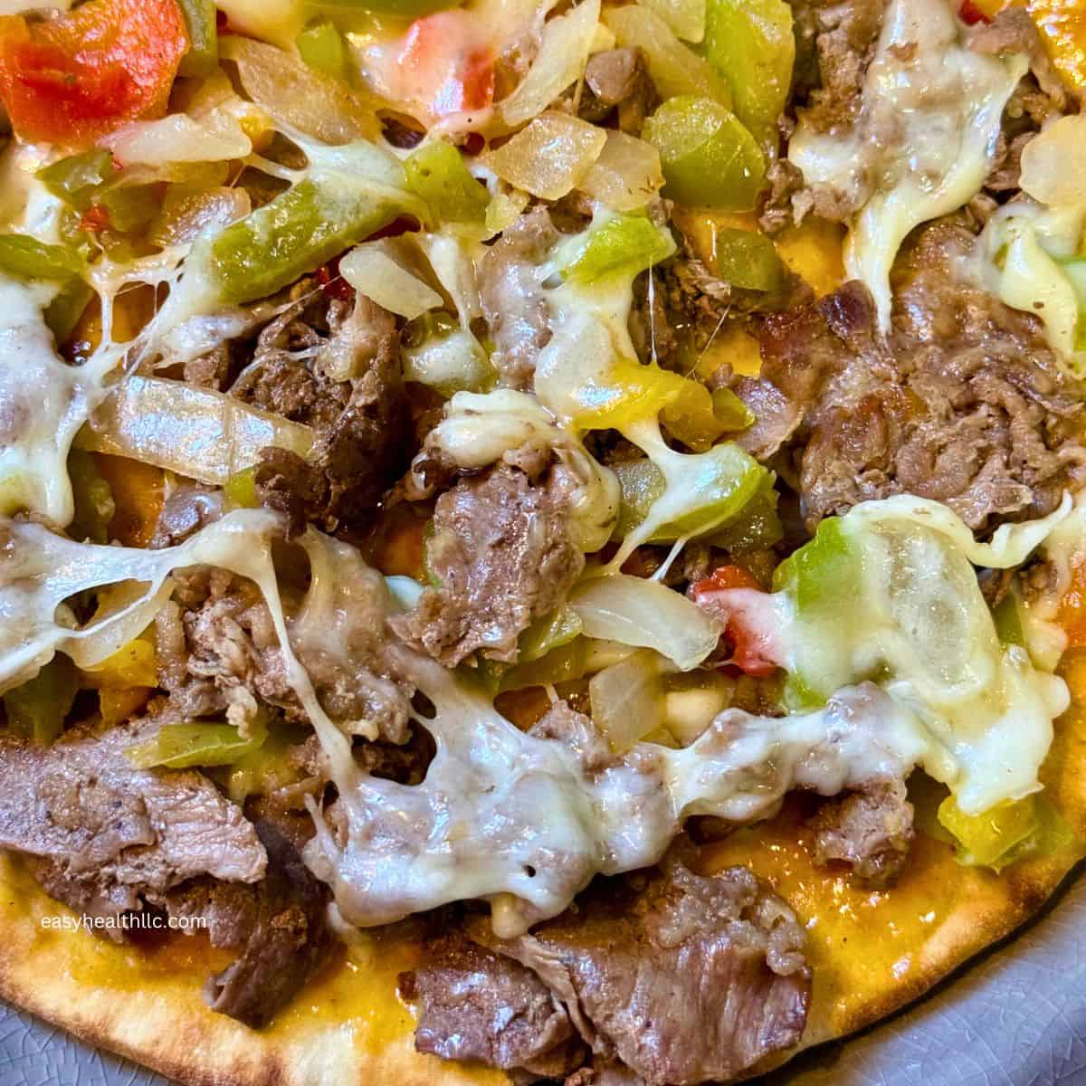 Shaved steak, peppers, onions and melted cheese on pita bread
