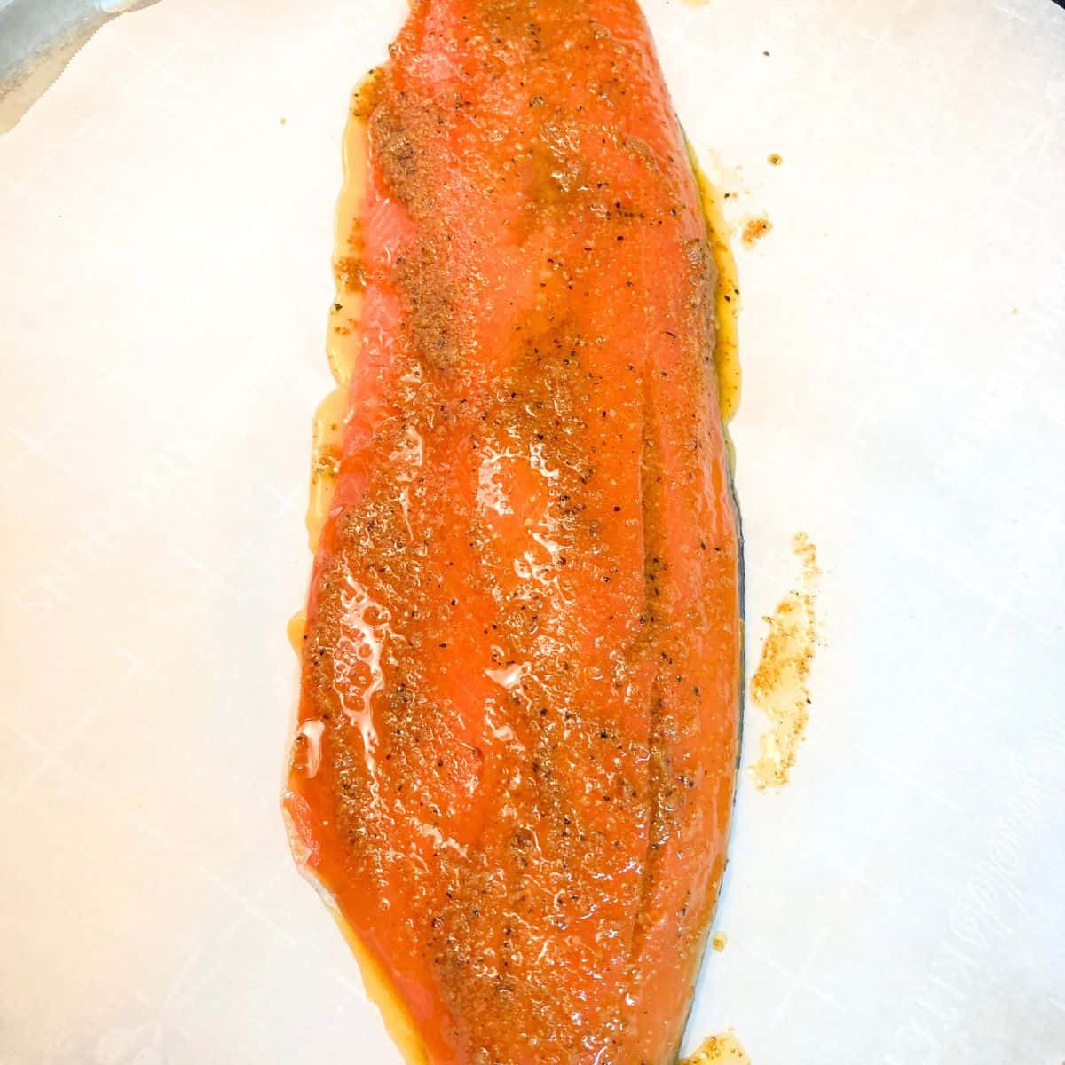Raw salmon filet on plate with seasonings added
